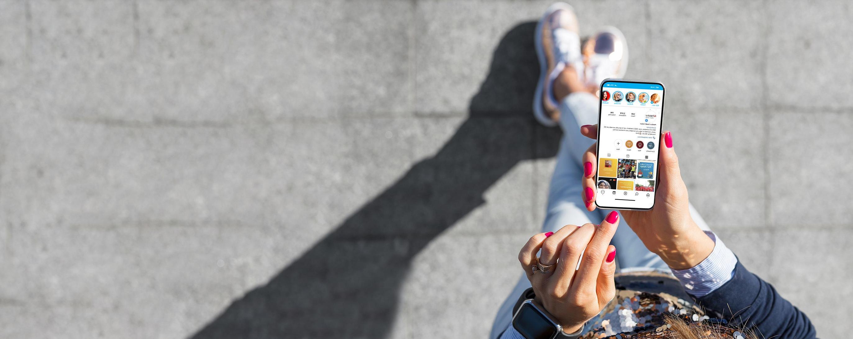 Person holding a phone displaying social media outside